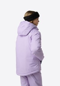 Μωβ μονωμένο μπουφάν με κουκούλα, με λεία υφή και διακριτικό λογότυπο. Συνδυασμένο με μαύρη πλεκτή κορδέλα για το κεφάλι.