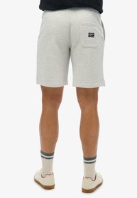 Pantaloni corti grigi in misto cotone con vita elasticizzata, tasca posteriore con patch del logo, abbinati a scarpe color crema e calze a righe multicolori.