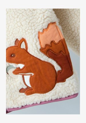 Purus kremiškas audinys su ruduo siuvinėtu voveriu, laikomu riešutą, ir dideliu oranžiniu lapu. Minkšta tekstūra, apvalios formos.