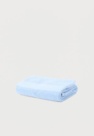 Light blue folded towel with a textured terry cloth surface on a plain white background.