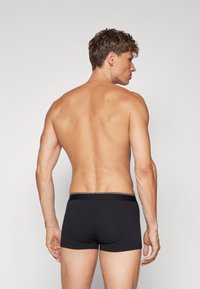 Svarta boxerkalsonger med en åtsittande design och elastisk midja. Slät textur, inga synliga mönster och en enkel sportig stil.