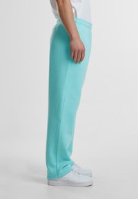 Light blue sweatpants made of soft fabric, featuring an elastic waistband and straight leg design, paired with white sneakers.