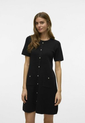 Must füüsilise ja lühikeste varrukatega kudum dress, millel on ümar kaelus, esine nööbistamine ning kaks värvitud taskut, kummaski hõbedane nööp.