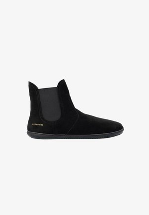 Stivaletto alla caviglia in suede nero con pannelli laterali elastici, suola piatta in gomma e logo "Groundies" nell'area del tallone.