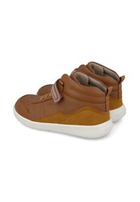 Botas de tobillo de cuero marrón y ante con suelas blancas, que cuentan con una correa de Velcro y punta perforada. Forro suave y diseño redondeado.