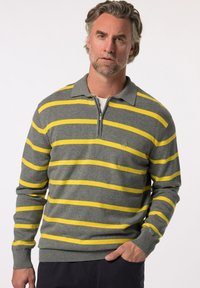 Grå tröja med gula horisontella ränder, dragkedjekrage, blandning av bomullsmaterial, ribbade manschetter och nederkant, med en liten logotyp på bröstet.