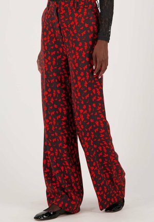 Pantalons à jambe large en tissu noir avec un motif floral rouge. Texture lisse avec une coupe décontractée, accentuée par une taille haute.