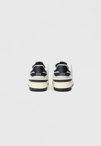 Αθλητικά παπούτσια σε λευκό και μαύρο χρώμα με υφή στο σχέδιο, με ανυψωμένη φτέρνα, επενδεδυμένο πέλμα και λογότυπο "LDN" στο πίσω μέρος. Μαύρη ελαστική σόλα.