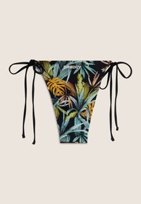 Bikini ala alha, iliyochapishwa na mimea ya tropiki yenye rangi ya kijani, njano, na nyeusi. Inamaonesha nyuzi za kubadilisha za rangi ya nyeusi upande wa kila upande na nembo ya "FREDDY."