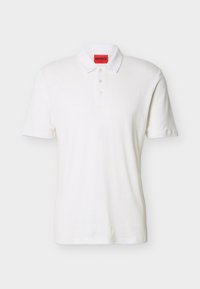 Polo blanc à manches courtes avec trois boutons et une étiquette de marque HUGO rouge à l'intérieur du col.
