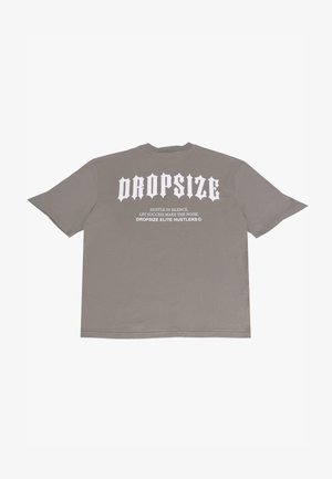 T-shirt gris oversize en coton. Présente un grand lettrage blanc au dos : "DROPSIZE" avec un slogan en dessous. Encolure ras du cou simpliste.