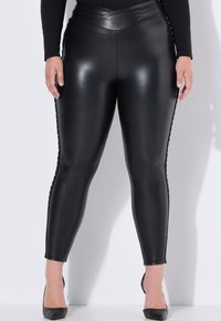 Zwarte neplederen leggings met een aansluitend ontwerp, voorzien van een gestreepte zijaccent en een schuine tailleband. Gladde afwerking.