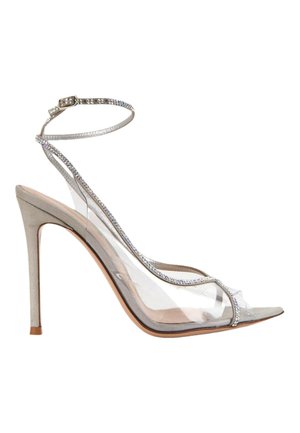 Sandale à talon haut avec des brides transparentes et une bride argentée à la cheville ornée de petits strass sur une semelle et un talon beige.