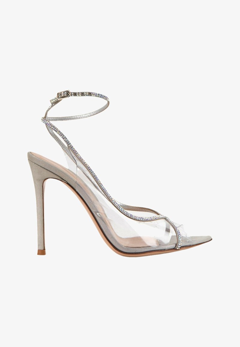 Sandale à talon haut avec des brides transparentes et une bride argentée à la cheville ornée de petits strass sur une semelle et un talon beige.
