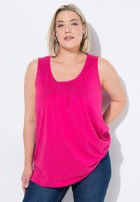 Top fucsia senza maniche con scollo rotondo e due pieghe al centro. Realizzato in tessuto morbido; vestibilità rilassata, abbinato a jeans blu scuro.