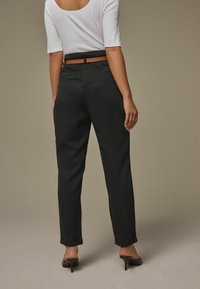 Crne krojene hlače s remenom, s uskim krojem i skraćenim rubovima. Uparene s pripijenom bijelom košuljom i crnim štiklama.