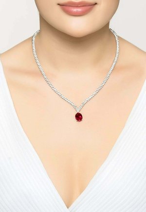 Silver necklace with a braided design, featuring a central red gemstone pendant. The chain is textured and shiny, enhancing the overall look.