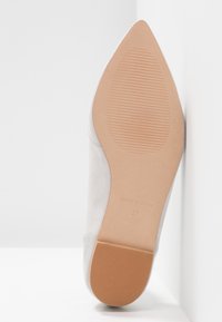 Semelle d'une chaussure blanche à bout pointu avec des grips texturés sur le talon et la plante, marquée "Made in Spain" et taille 37.