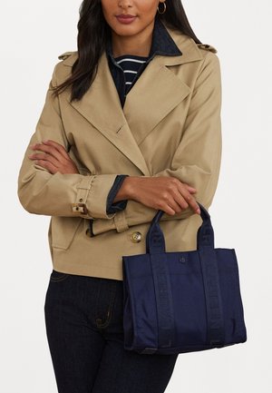 Marineblå tote bag med "LAUREN" tekst på håndtagene, lavet af et blødt materiale. Udformet med en kvadratisk form og minimalistisk design.