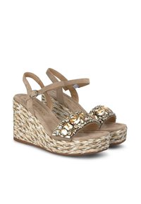 Sandali con zeppa beige con due cinturini regolabili. Caratterizzati da una base in juta tessuta con texture e da un elegante adornamento in strass sulla parte superiore.