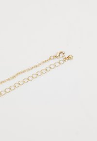 Goldene Kettenarmband mit verbundenen ovalen Formen, einem Karabinerverschluss und einem runden Perlenakzent, der einen polierten metallischen Glanz zeigt.