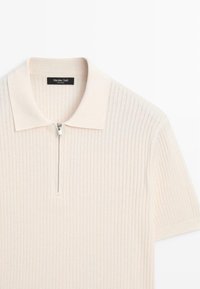 Polo a maniche corte crema a coste con zip argentata a un quarto e colletto piegato, etichettata Massimo Dutti.