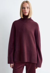 Burgunderfarbener Strickpullover mit hohem geripptem Kragen, weiten Ärmeln und geripptem Saum. Weiche Textur mit einer lässigen Passform.