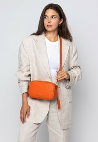 Orangefarbene Leder-Crossbody-Tasche mit rechteckiger Form, kontrastierendem Träger, silbernen Beschlägen und glatter Textur.