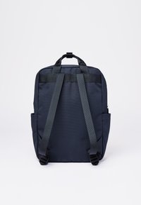 Laadittu tummansininen reppu, jossa on kaksi pehmustettua olkahihnaa, yläkahva, sivutaskut ja rakenteellinen, suorakulmainen muoto.