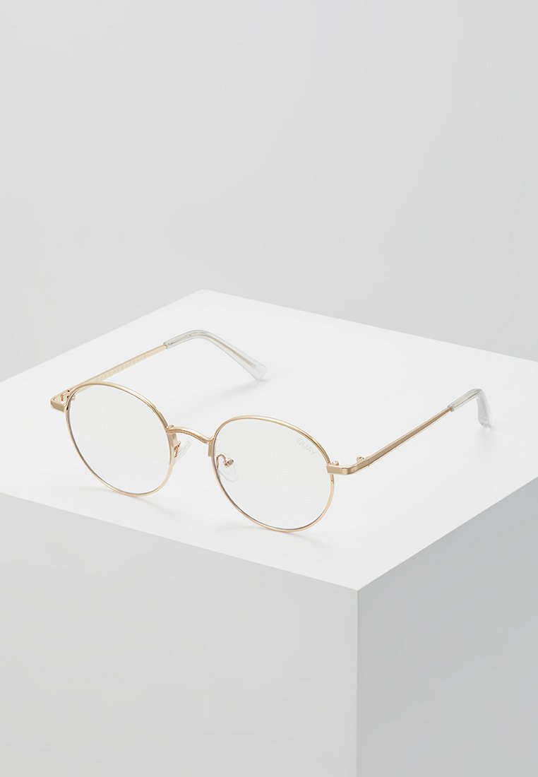 Lunettes en métal doré avec une monture ovale, des verres transparents et des accents argentés sur les branches. Design épuré avec des détails minimalistes.