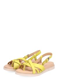 Żółte skórzane sandały z krzyżującymi się paskami i zapięciem na kostkę. Płaska podeszwa w jasnym odcieniu beżu, o gładkiej teksturze i minimalistycznym designie.