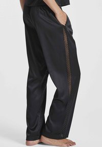 Pantalons de pyjama en satin noir avec une coupe décontractée, dotés de poches latérales et d'un panneau en maille transparente à motif diamant le long des coutures extérieures.