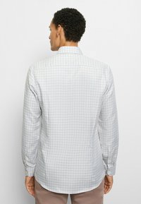 Langärmliges Hemd zum Knöpfen aus hellgrauem Stoff mit einem karierten Muster in Blau und Beige. Verfügt über einen abgerundeten Saum und geknöpfte Manschetten.