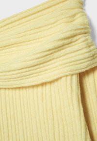 Gelber gerippter Strickstoff mit einer weichen Textur, der ein gefaltetes Design aufweist. Das Muster ist durchgängig mit vertikalen Linien.