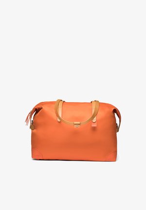 Sac de sport rectangulaire orange avec poignées couleur beige, une sangle à pression à l'avant, une fermeture éclair sur le dessus et une petite étiquette rouge sur le côté droit avant.