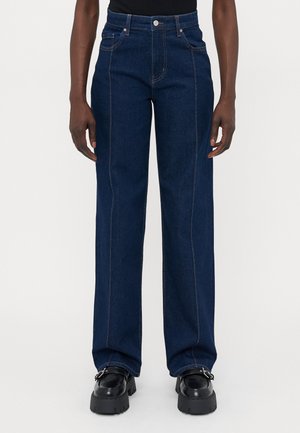 Donkerblauwe denim jeans met een hoge taille, wijde pijpen, contrasterende stiksels en voorkruiszakken. Einde net boven de schoenen.
