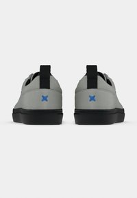 Γκρι αθλητικά παπούτσια με μαύρες σόλες, που διαθέτουν μαύρη θηλιά έλξης και μπλε λεπτομέρειες στη φτέρνα, με ομαλή υφή και μινιμαλιστικό σχέδιο.