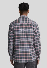Camicia a maniche lunghe con motivo a quadri in verde scuro, rosso e bianco, polsi abbottonati e colletto classico con dettaglio a piega sul retro.