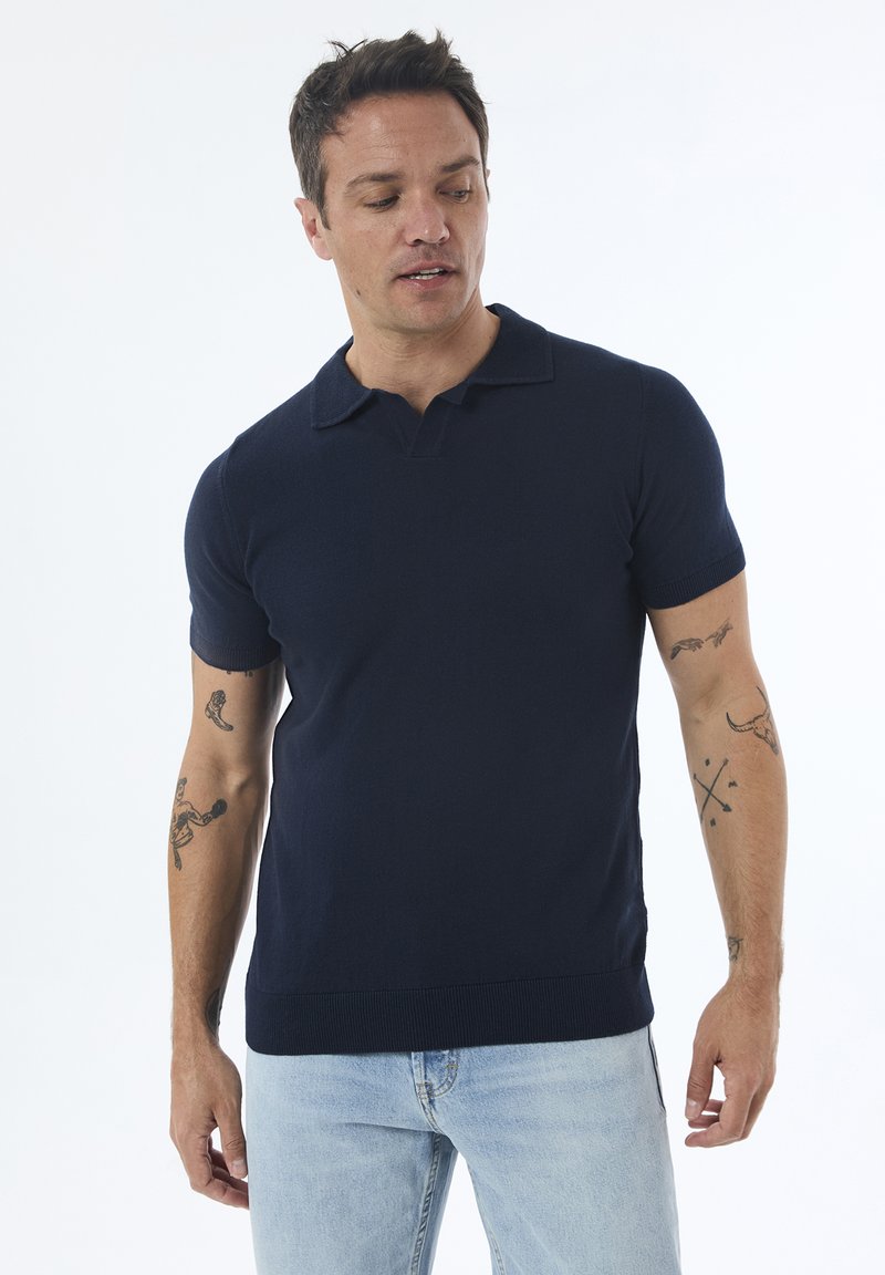 Mørkeblå polo t-shirt med krave og korte ærmer, lavet af et glat, strækbart materiale. Har ribbet kant og et minimalistisk design.