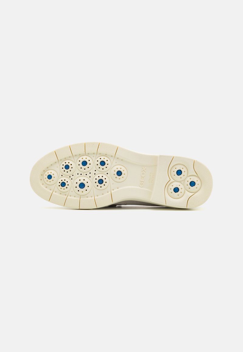 Suela de zapato beige con patrones de agarre circulares en azul y negro, surcos flexibles y "GEOX PATENTE ITALIANA" grabado en la zona del arco.