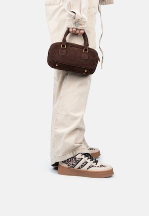 Sac à main en daim marron avec des poignées courtes, associé à un pantalon large beige et des baskets beiges avec un imprimé léopard et des accents noirs.