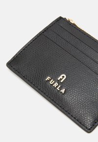 Black leather cardholder with a textured finish, featuring multiple card slots and a gold-tone logo. Compact rectangular shape.