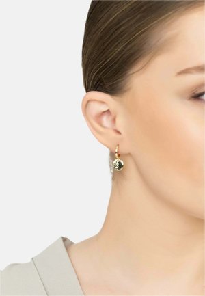 Goldene Creolen mit einem strukturierten, runden Anhänger, der eine polierte Oberfläche und ein zartes Design betont. Trägt das Ohr eines Modells.