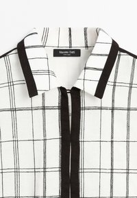 Bílá košile s černým mřížkovým vzorem, černým lemováním podél límce a légou, štítek Massimo Dutti, vyrobeno v Indii.