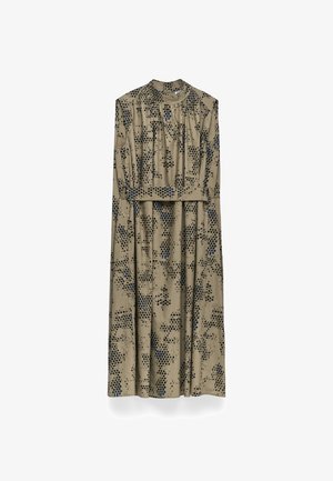 Langes, beigefarbenes Kleid mit hohem Kragen und kurzen Ärmeln, das ein dunkelblaues Pünktchenmuster aufweist. Das Kleid hängt vor einem weißen Hintergrund.