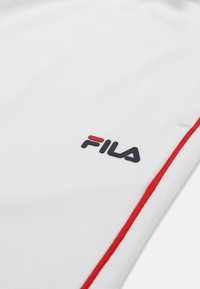 Tissu blanc avec un logo FILA noir et rouge et une rayure rouge parallèle au bord.