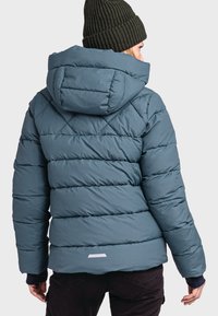 Türkisfarbene Daunenjacke mit Kapuze, gestepptem Design und gerippten Akzenten. Verfügt über ein weißes Etikett am unteren Rücken. Weiches, isoliertes Material.