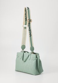 Žalias tekstūruotas odinis rankinukas su iškilniu logotipo dizainu, dviem rankenomis ir nuimamu dryžuotu dirželiu, ant kurio juodai užrašyta "VALENTINO".