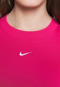Přiléhavé růžové bavlněné tričko s kulatým výstřihem a krátkými rukávy, na hrudi s malým bílým vyšitým logem Nike.