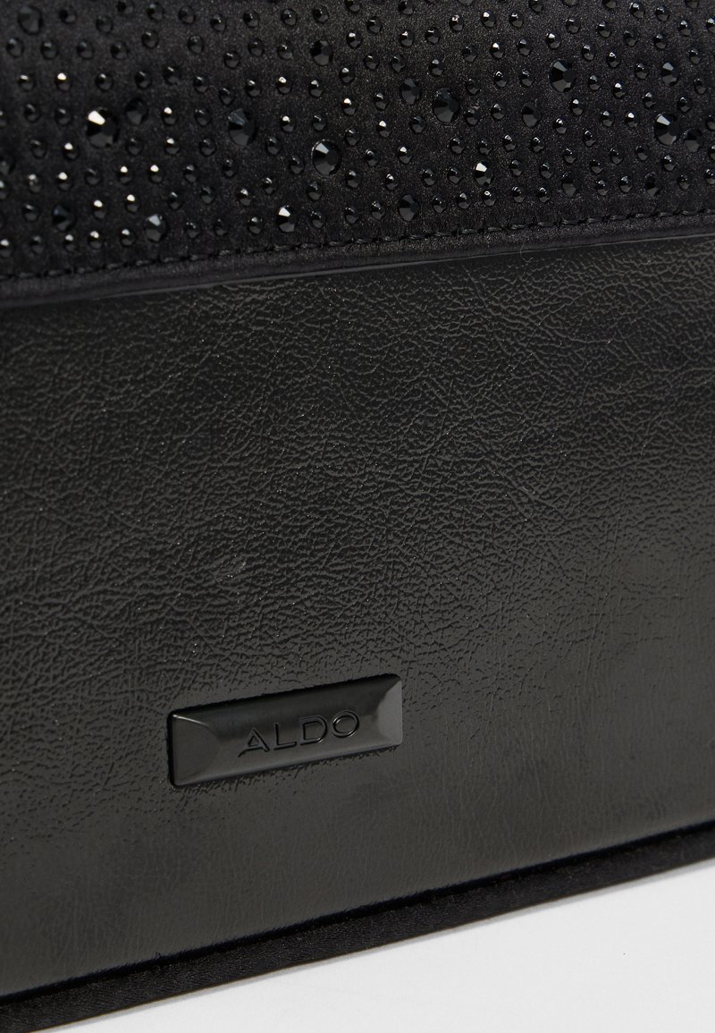 Borsa nera con parte superiore texturizzata arricchita da perline trasparenti, sezione inferiore liscia e targhetta nera con logo.